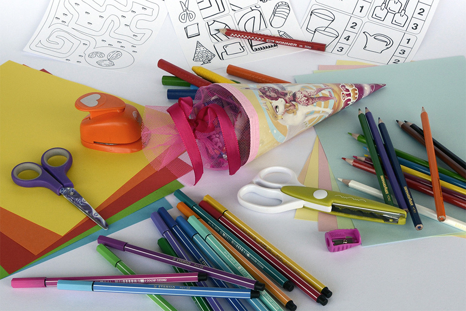 Papper, färgpennor och sax på ett bord