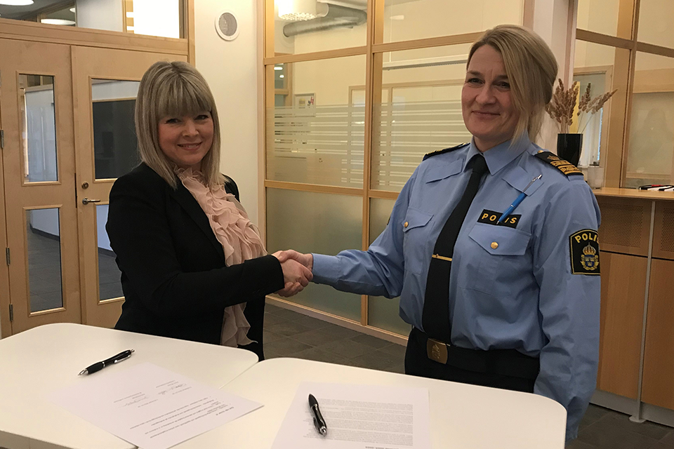 Julia Färjhage, kommunstyrelsens ordförande tillsammans med Jenny Wester, lokalpolisområdeschef Östra Fyrbodal. De tar leende i hand över de påskrivna pappren.