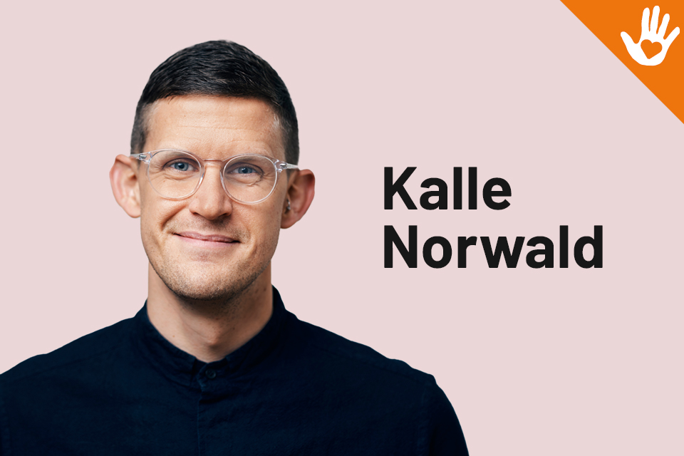 Bilden visar Kalle Norwald i halvkropp, iklädd rosa skjorta och svarta glasögon.