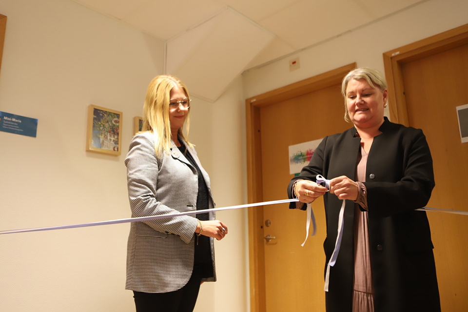 Bilden visar Maria Lundh, enhetschef öppenvården, och Pernilla Sundemar, verksamhetschef för individ- och familjeomsorgen, som knyter en rosett av invigningsband.