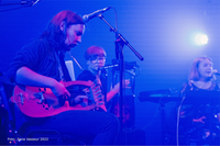 Ett band spelar på scen, i blått motljus