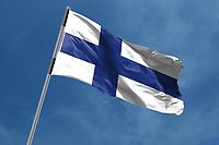 Finlands flagga som svajar högst upp i en flaggstång.