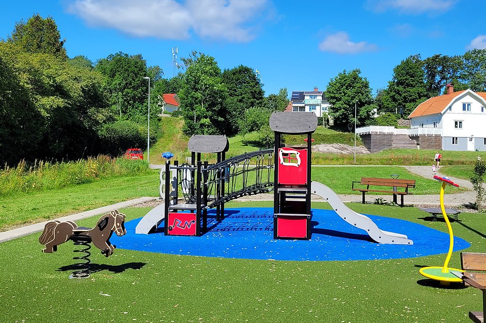 Bild på lekplats med en brun gunghäst och en röd klätterställning