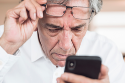 Äldre man tittar bekymrat ner på telefonen