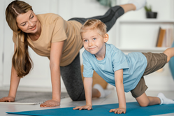 Mamma och son tränar tillsammans på yogamattor. 