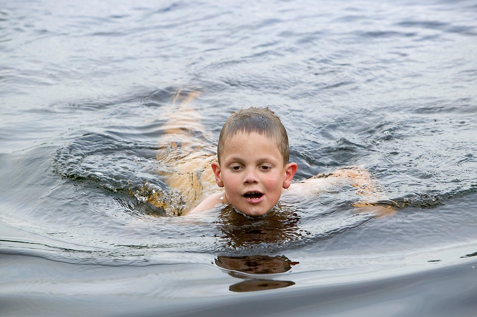 Pojke som simmar i en sjö